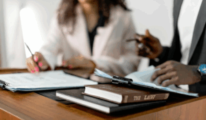 Two people reviewing legal documents at a desk with law books